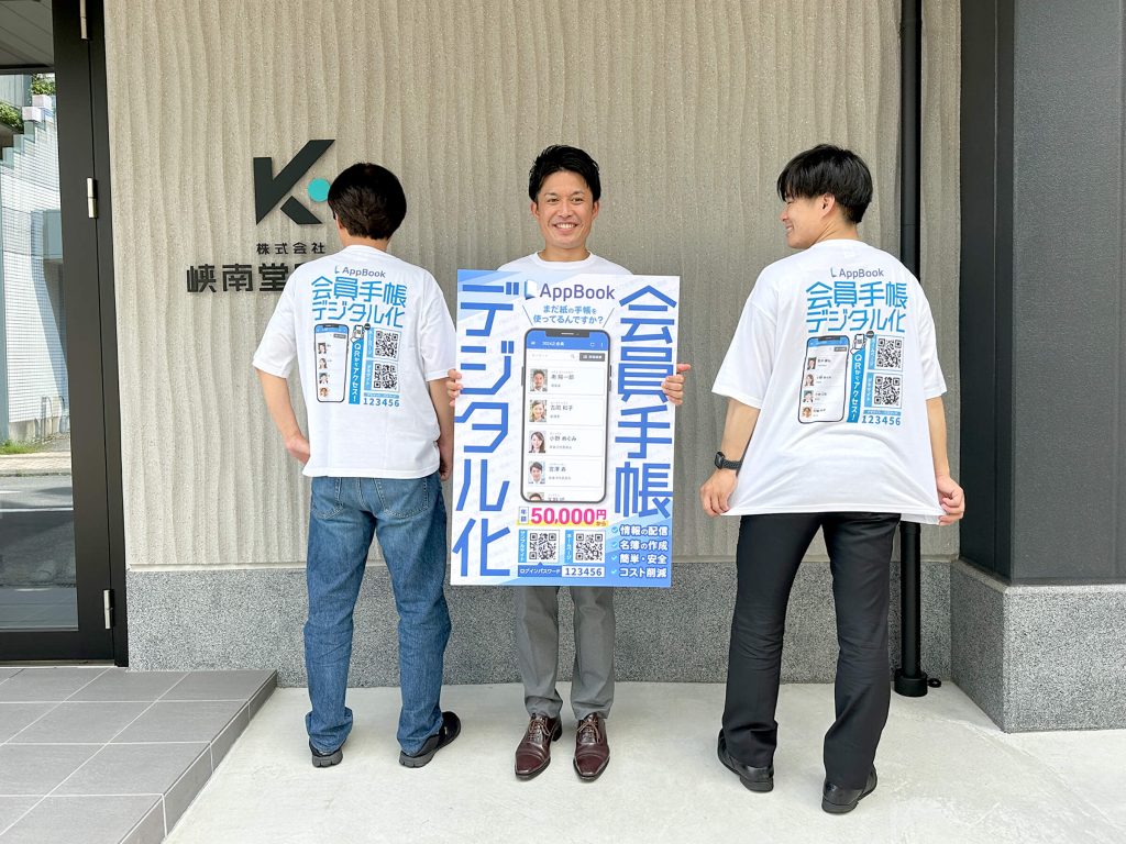 AppBookのTシャツを着て、パネルを持つ３人